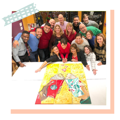 A corporate group gathered around their completed collaborative canvas mural