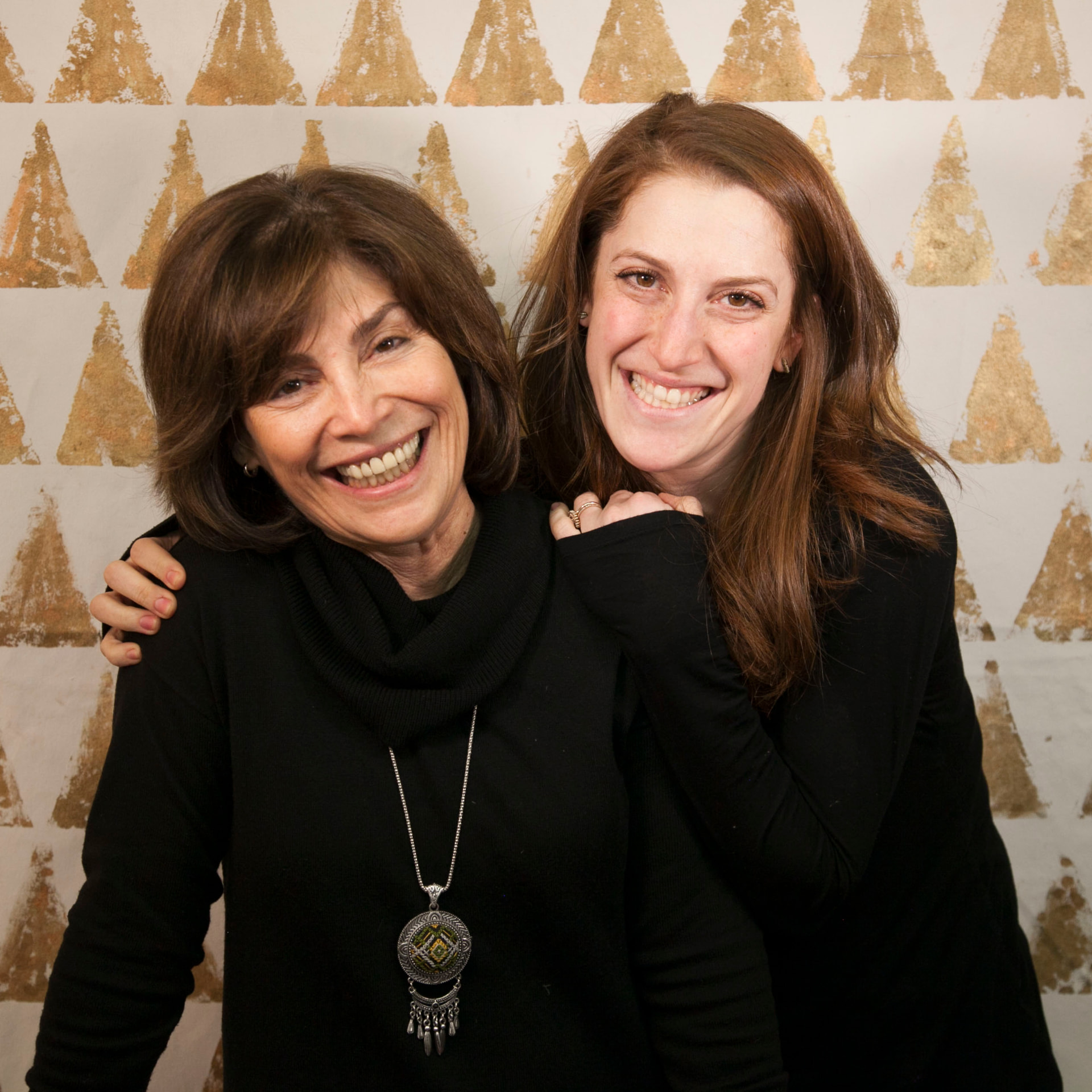 Jill and Jackie smiling together in front of the gold triangle mural
